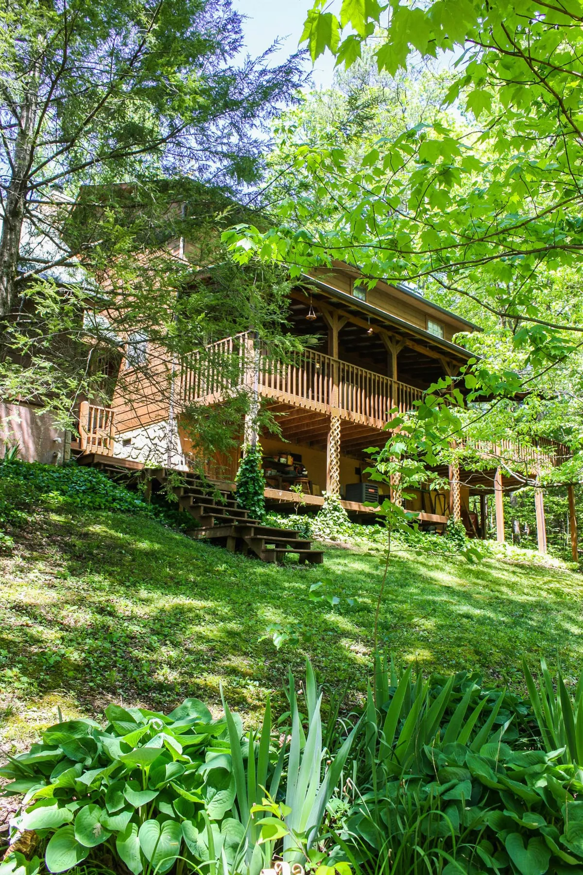 A wooden deck bordered by lush greenery, offering a serene outdoor retreat. The stepped pathway and natural surroundings suggest an ideal spot for grilling, relaxing, or enjoying nature after a homemade meal.